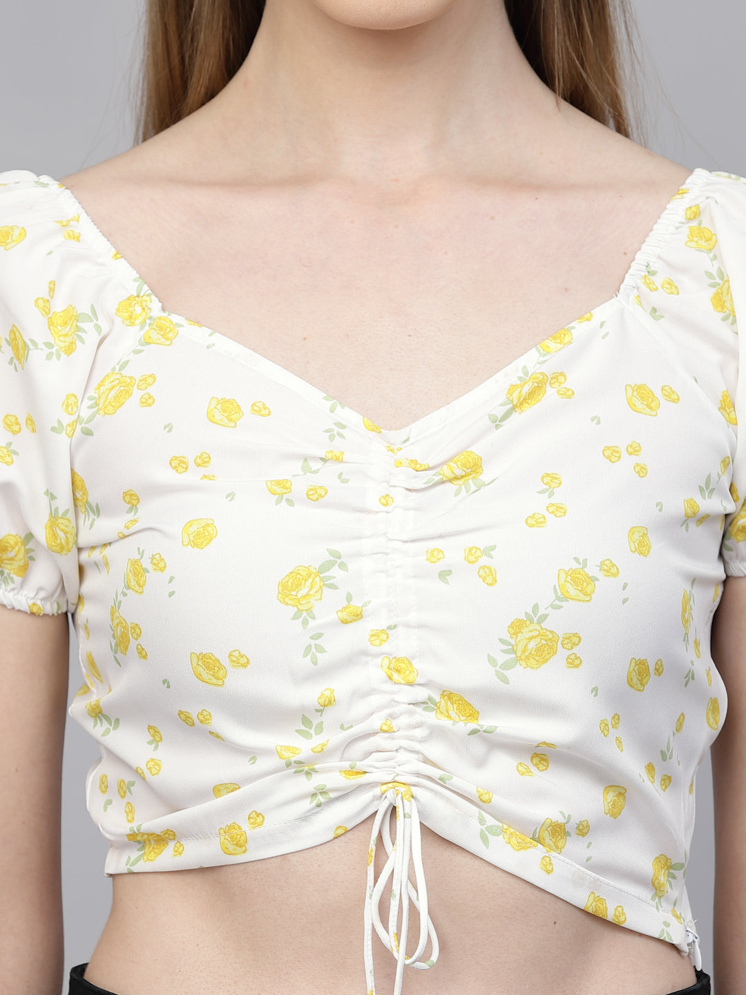 White top with yellow floral pattern and tied front, on a plain background