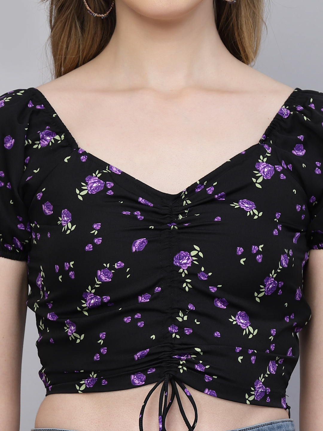 Black top with purple floral pattern worn by a person on a gray background