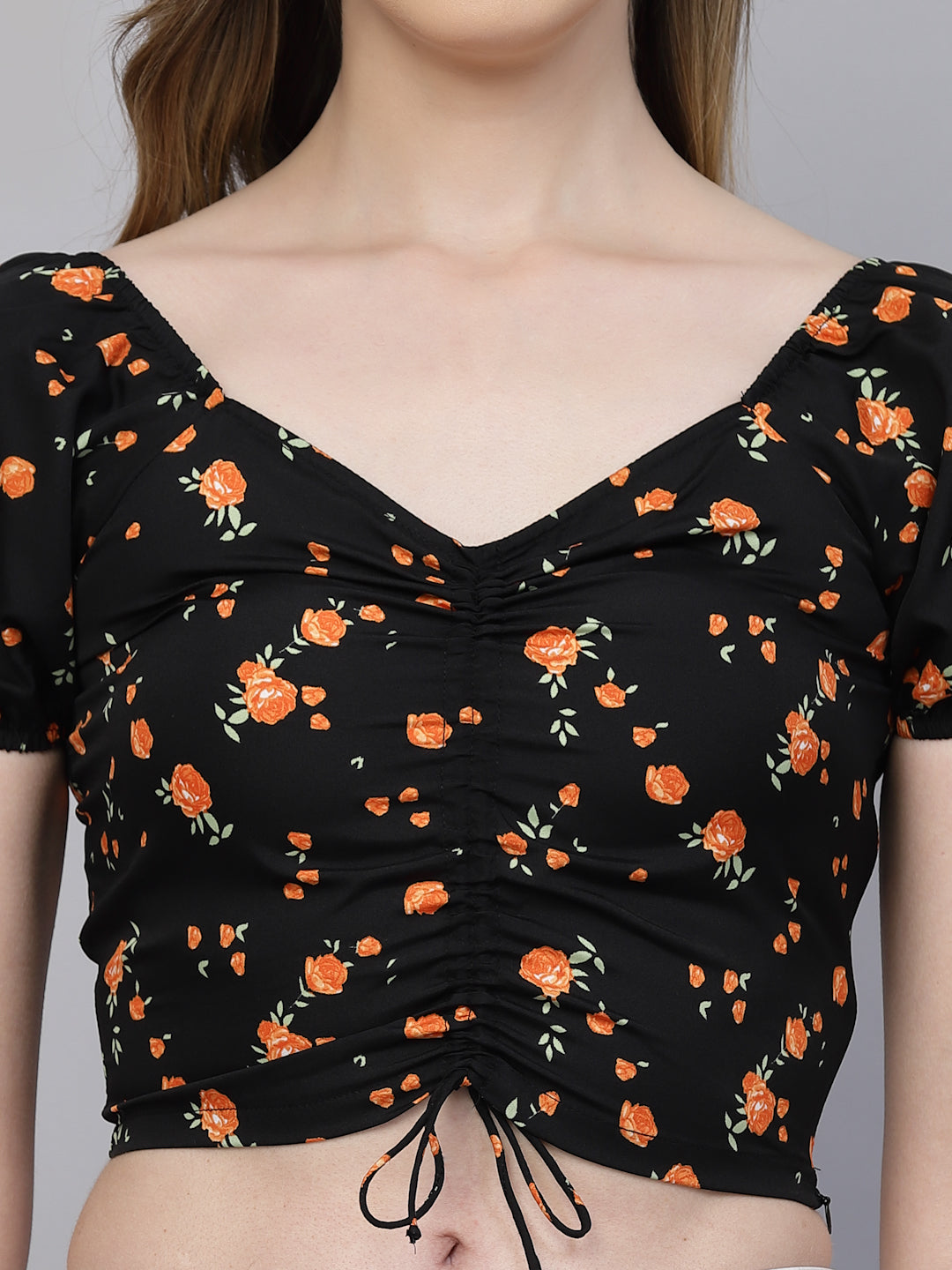 Black crop top with orange floral pattern worn by a person on a gray background