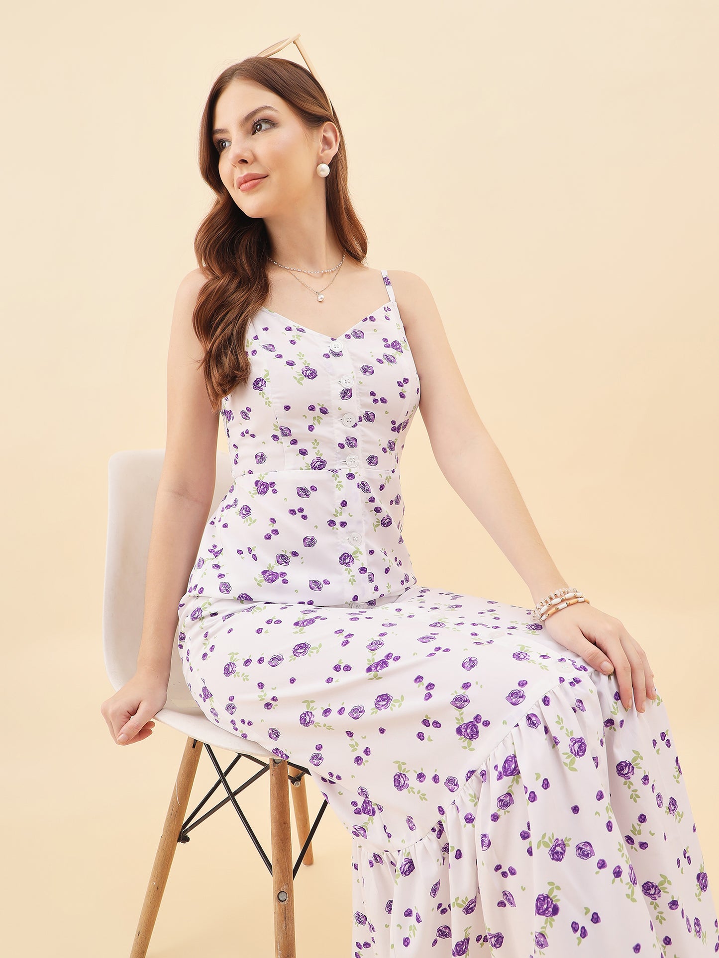 Woman wearing a floral dress sitting on a chair against a beige background