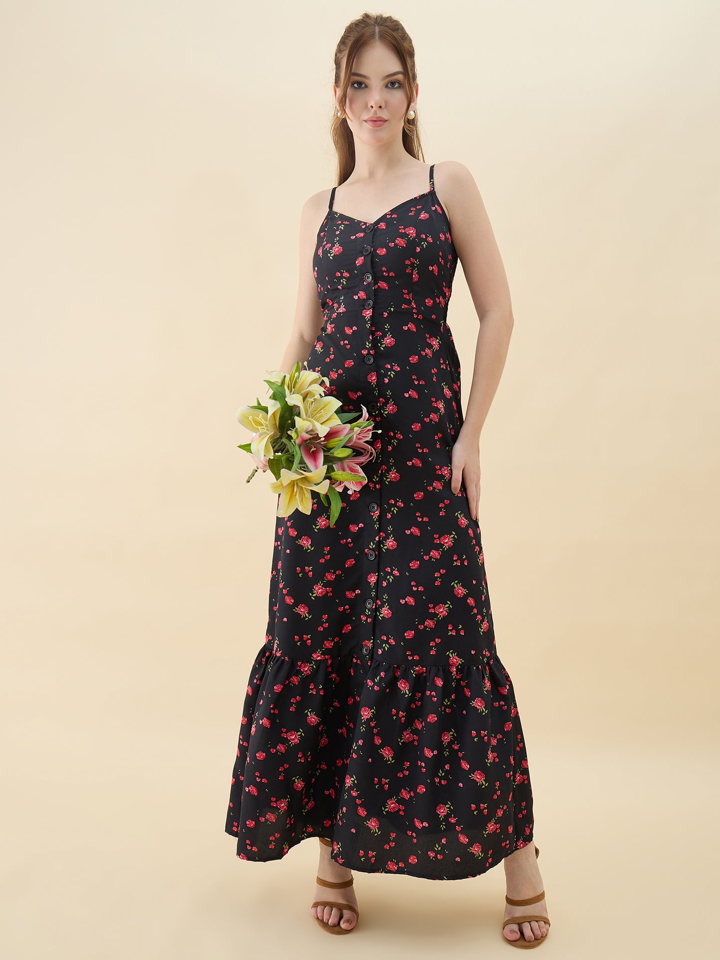 Woman wearing a black floral dress holding flowers against a beige background