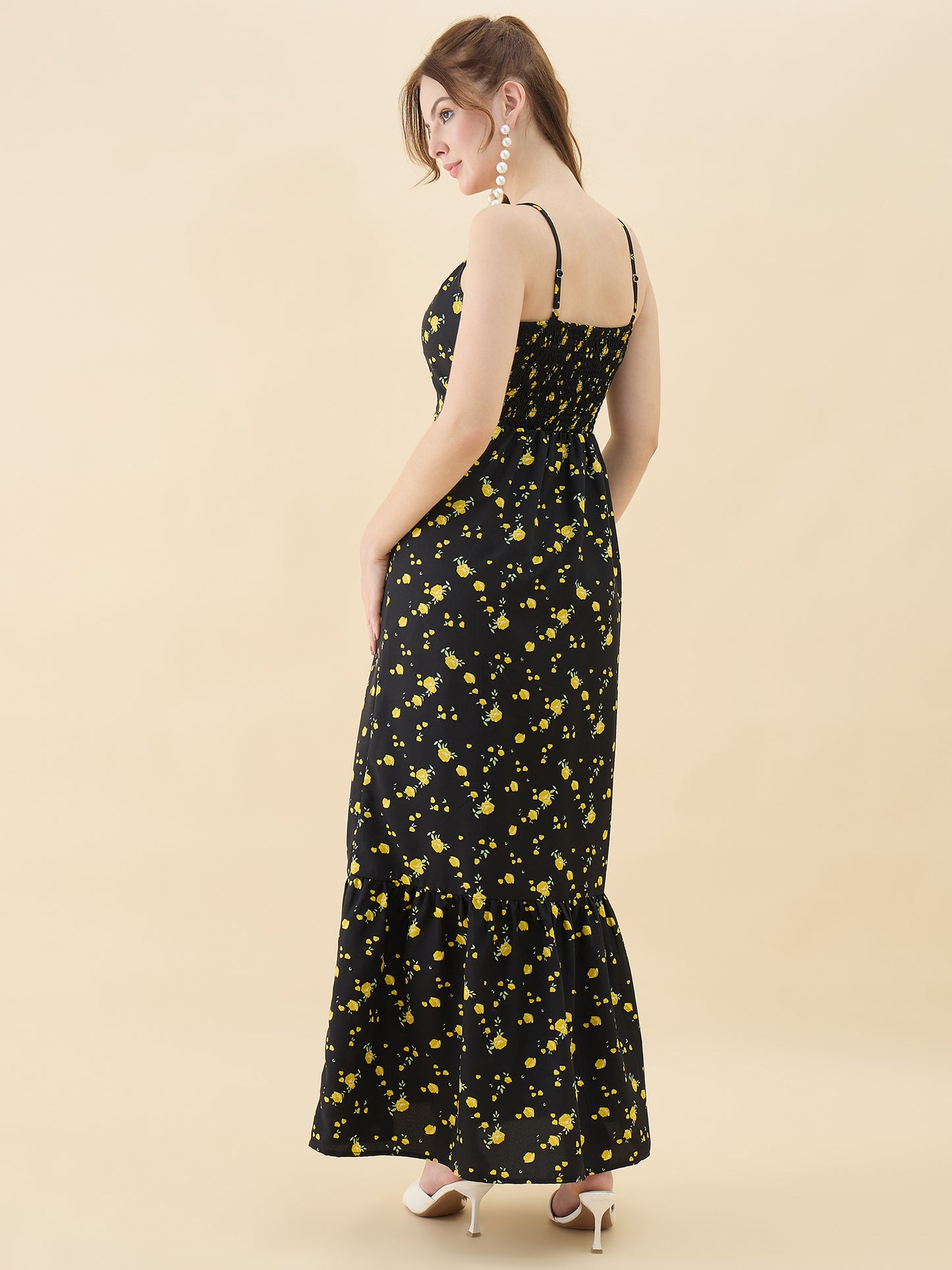 Woman wearing a black dress with yellow floral patterns on a beige background