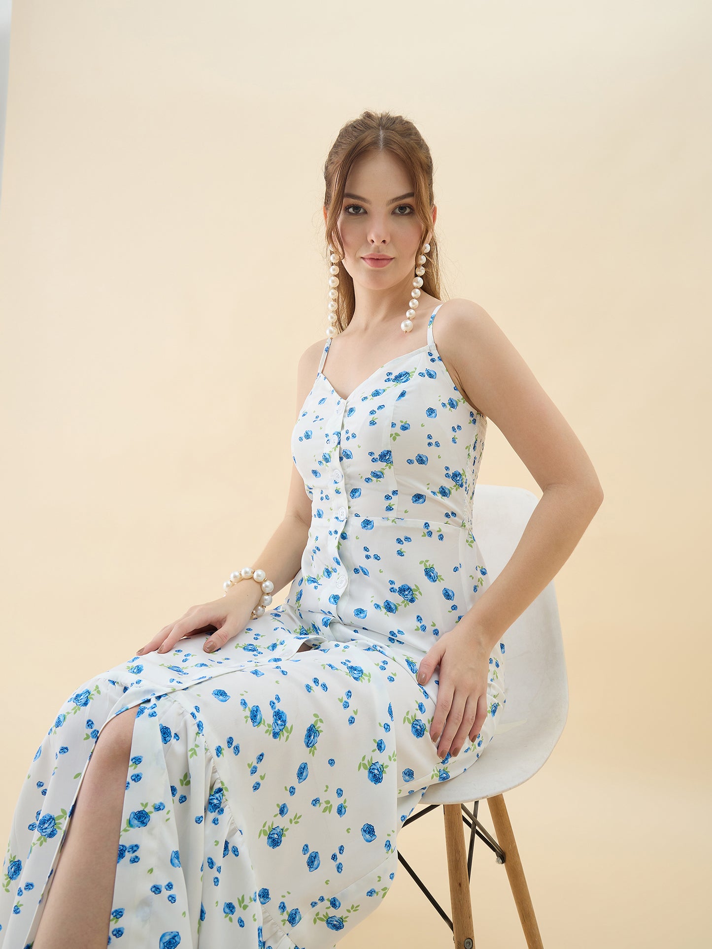 Woman wearing a floral dress sitting on a chair against a beige background