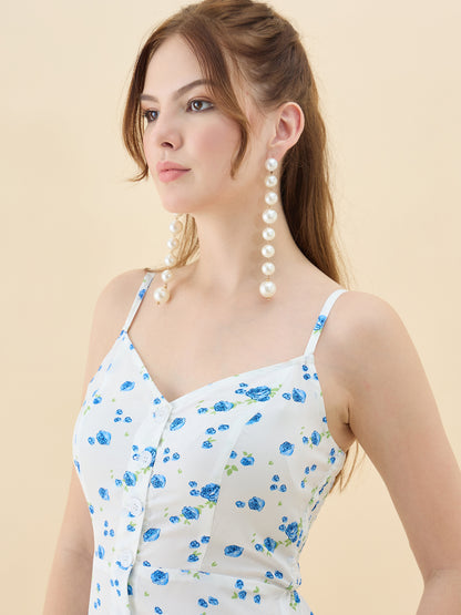 Woman wearing a white dress with blue floral patterns and pearl earrings on a beige background