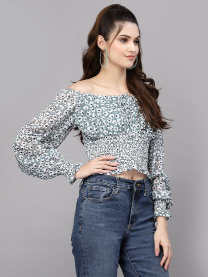 Woman wearing a green floral blouse and jeans on a gray background