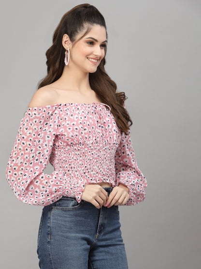 Woman wearing a pink floral off-shoulder top and blue jeans on a gray background
