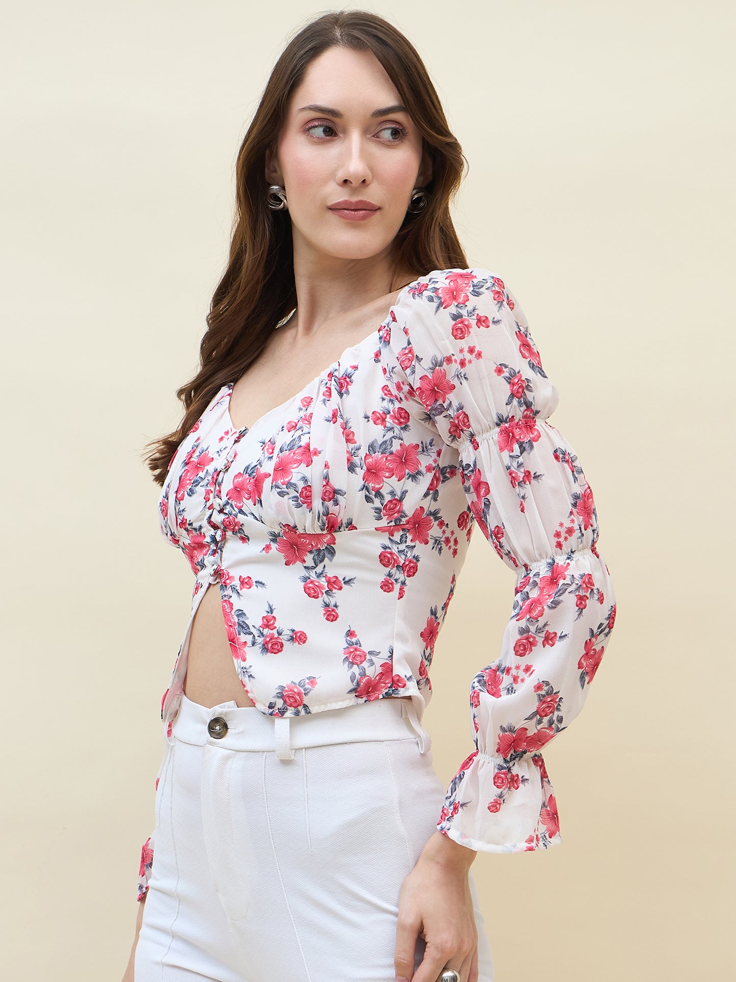 Woman wearing a white & pink floral top with long sleeves on a beige background