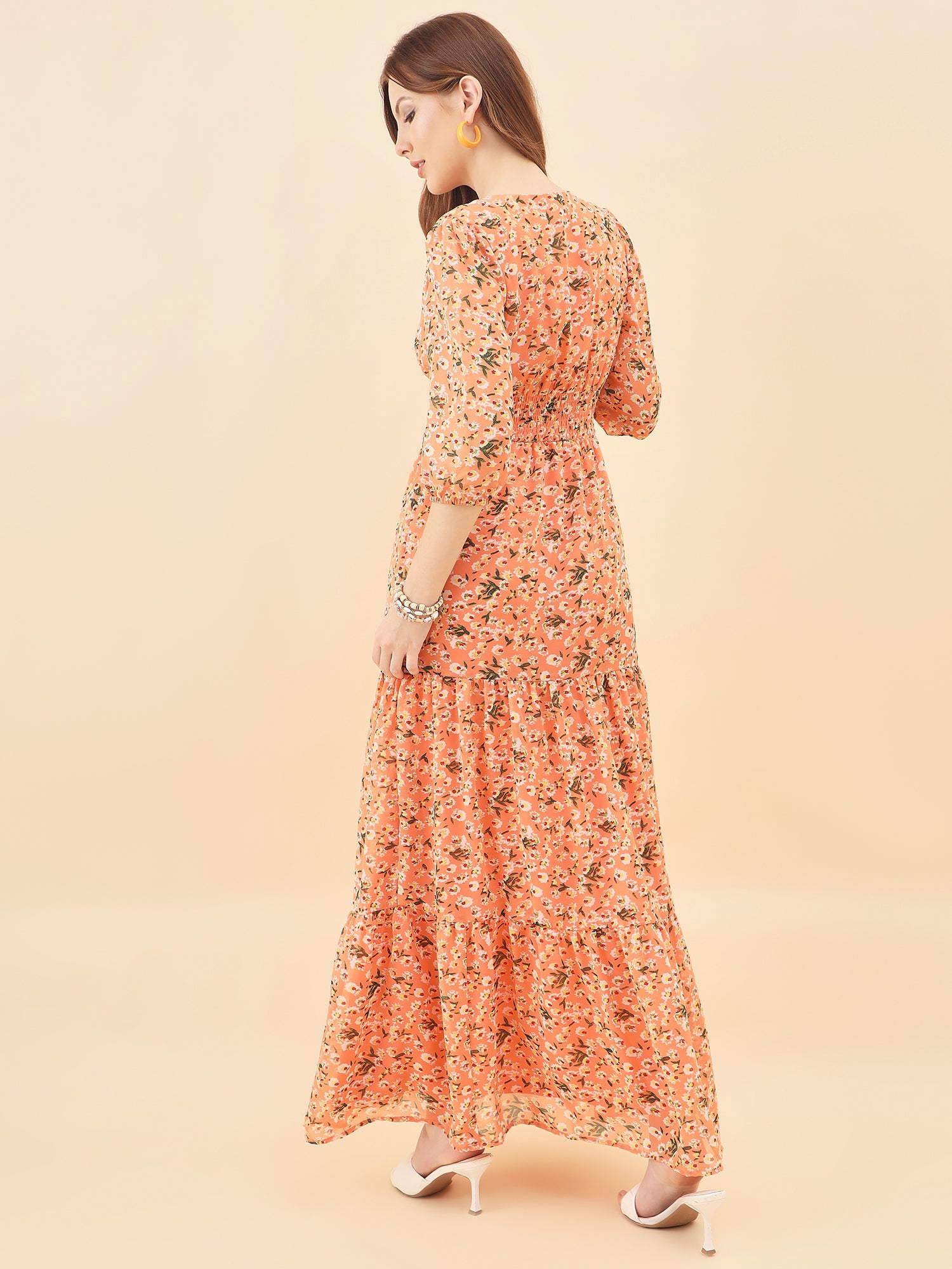 Woman wearing a orange floral dress on a beige background