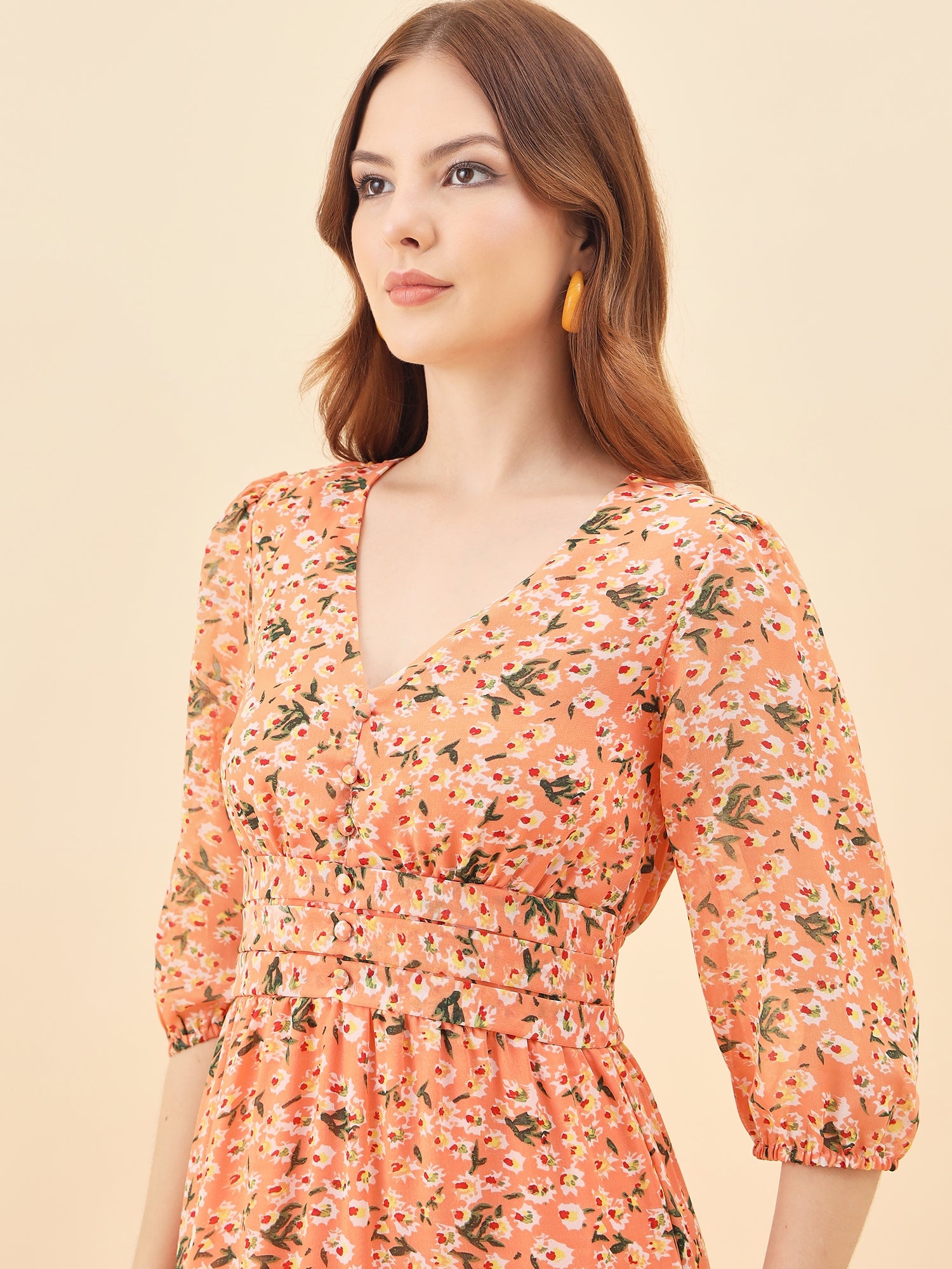 Woman wearing a orange floral dress against a beige background