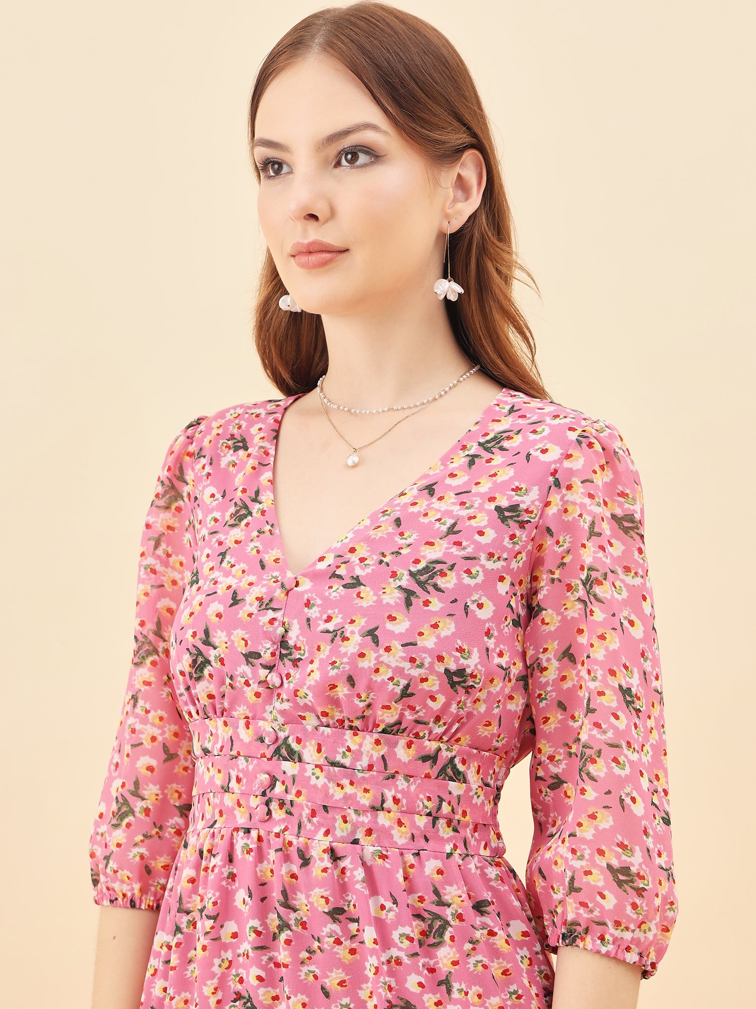 Woman wearing a pink floral dress against a beige background