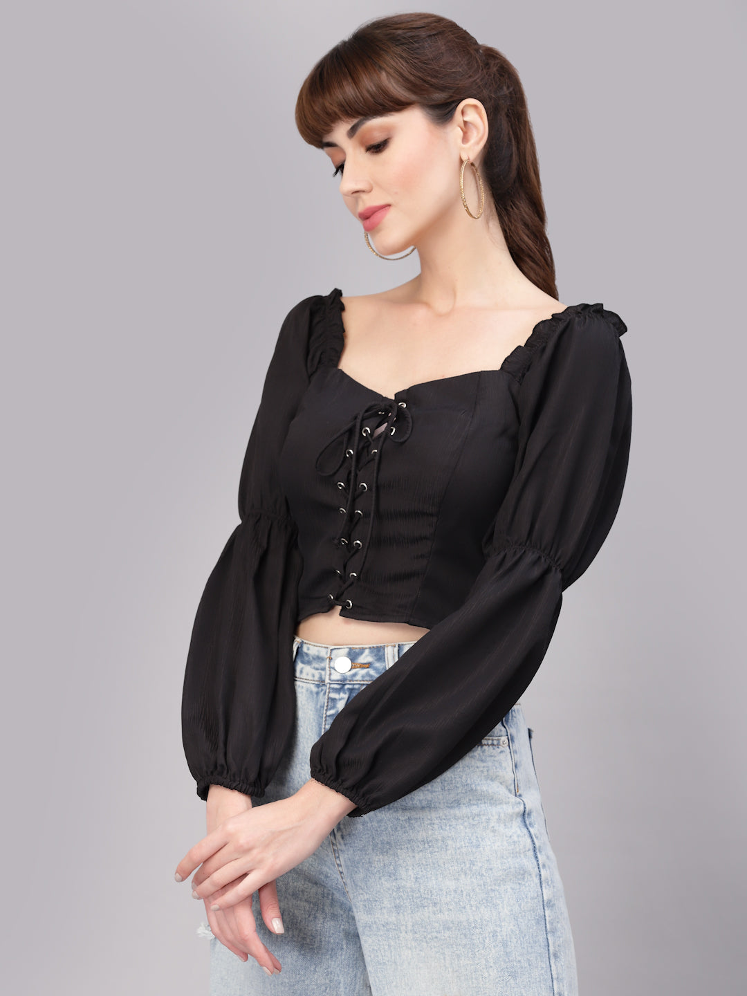 Woman wearing a black top with puffed sleeves on a gray background