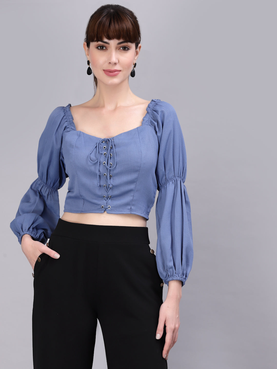 Woman wearing a light blue blouse with puffed sleeves against a gray background