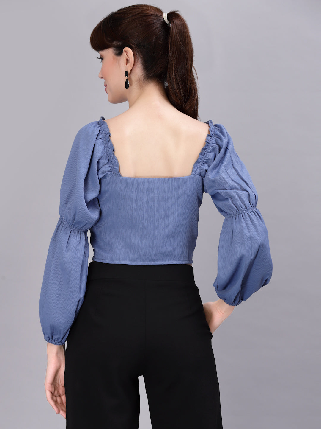 Woman wearing a light blue top with puffed sleeves on a gray background