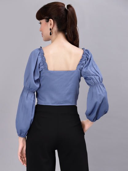 Woman wearing a light blue top with puffed sleeves on a gray background