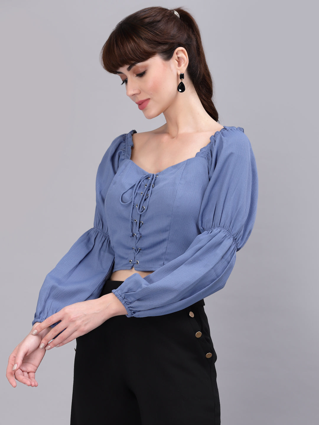 Woman wearing a light blue top with puffed sleeves on a gray background