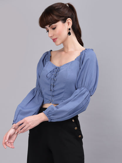 Woman wearing a light blue top with puffed sleeves on a gray background