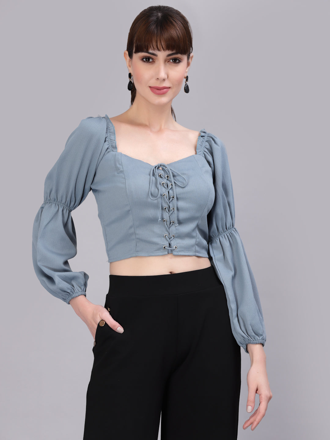 Woman wearing a light green top with puffed sleeves against a gray background