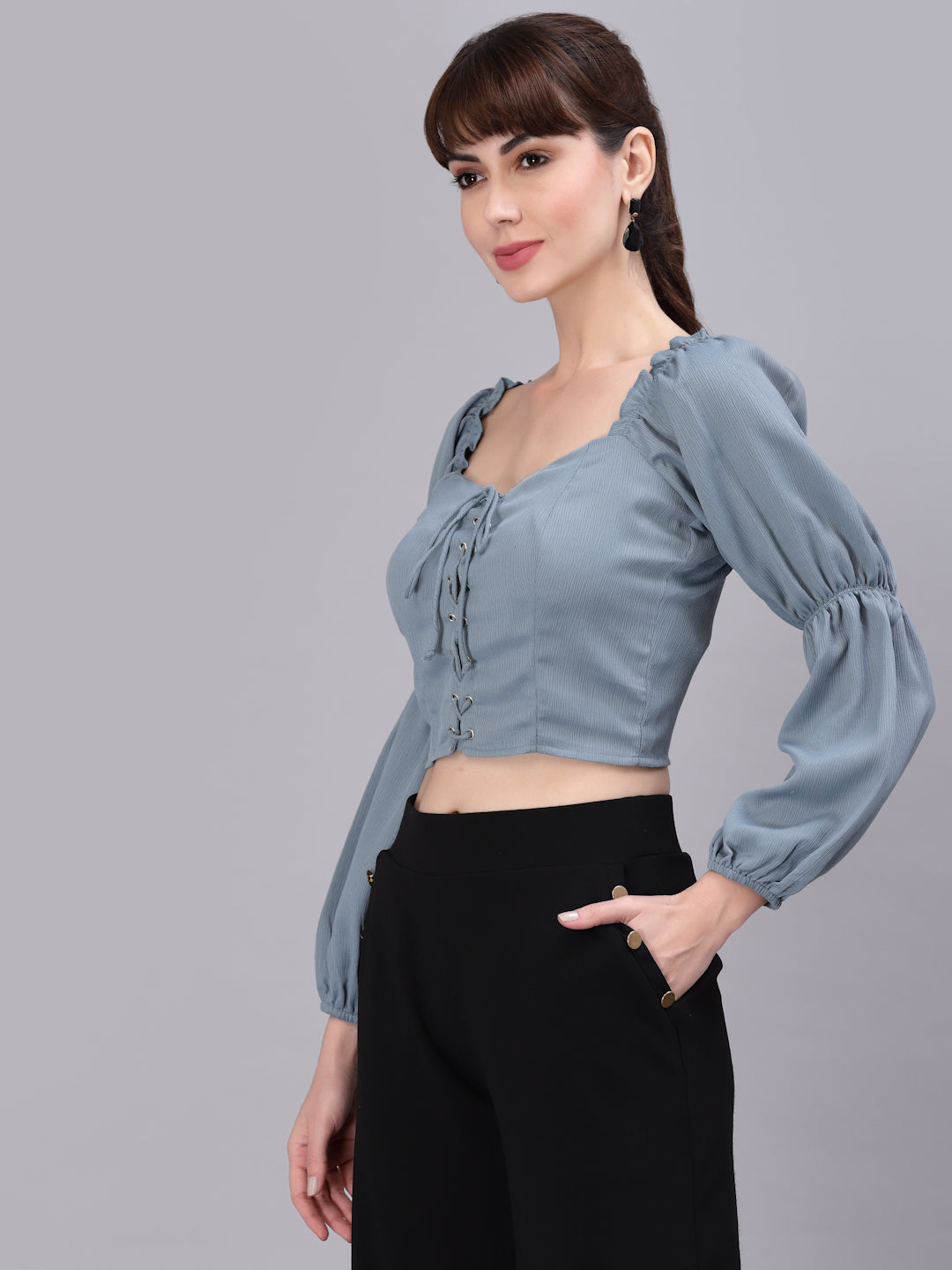 Woman wearing a light green top with puffed sleeves against a gray background