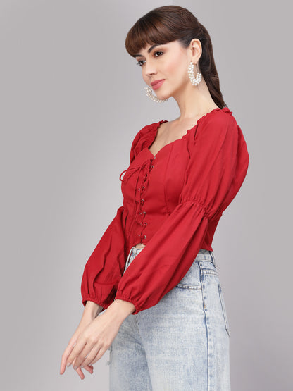 Woman wearing a red top with puffed sleeves against a gray background