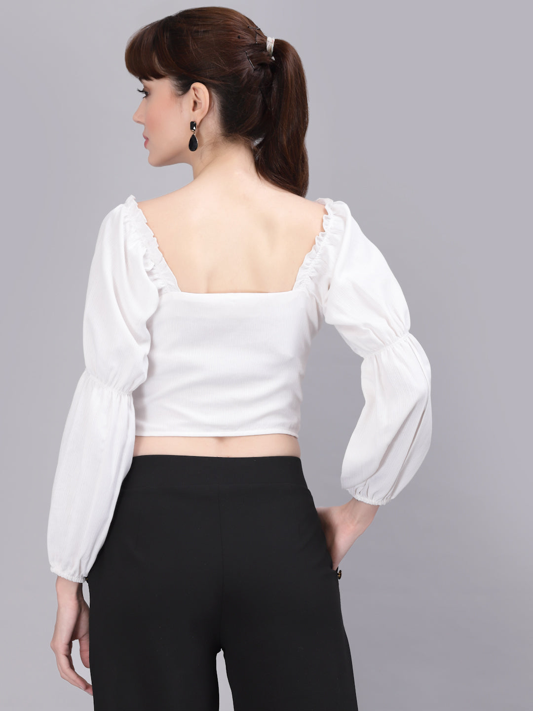 Woman wearing a white top with puffed sleeves on a gray background