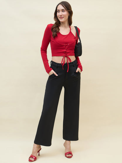 Woman wearing a red top and black pants against a beige background