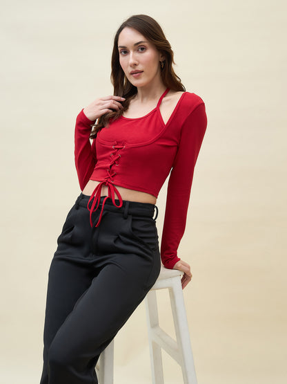 Woman wearing a red long-sleeve crop top and black pants on a beige background