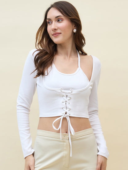 Woman wearing a white long-sleeve top with a lace-up design and beige pants on a beige background