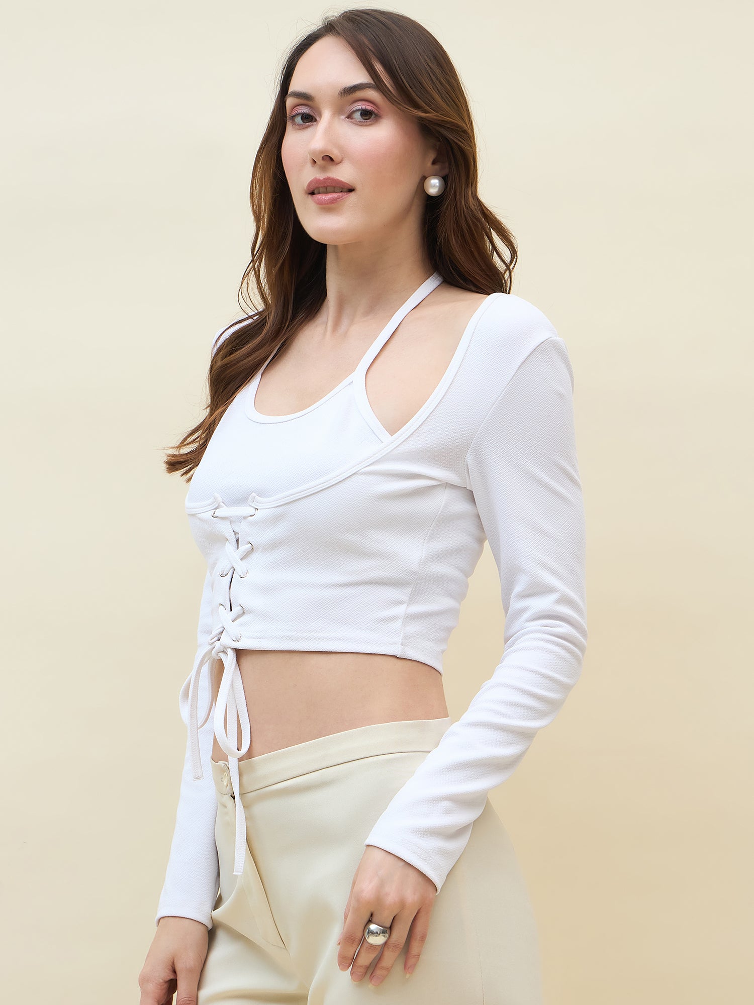 Woman wearing a white long-sleeve crop top with a beige background