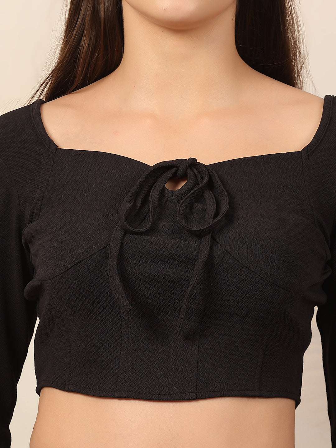 Black crop top with a bow detail on a neutral background