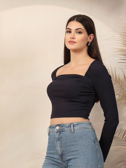 Woman wearing a blue long-sleeve top and blue jeans against a neutral background