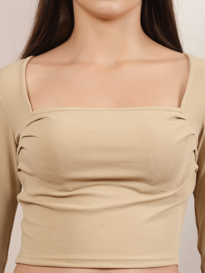 Beige long-sleeve top worn by a person on a plain background
