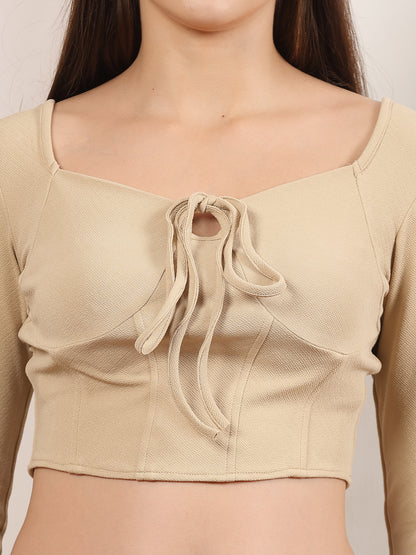 Beige top with a bow detail on a plain background