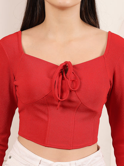 Red crop top with a tie detail worn by a person on a plain background