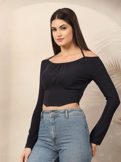 Woman wearing a blue long-sleeve crop top and blue jeans against a beige background