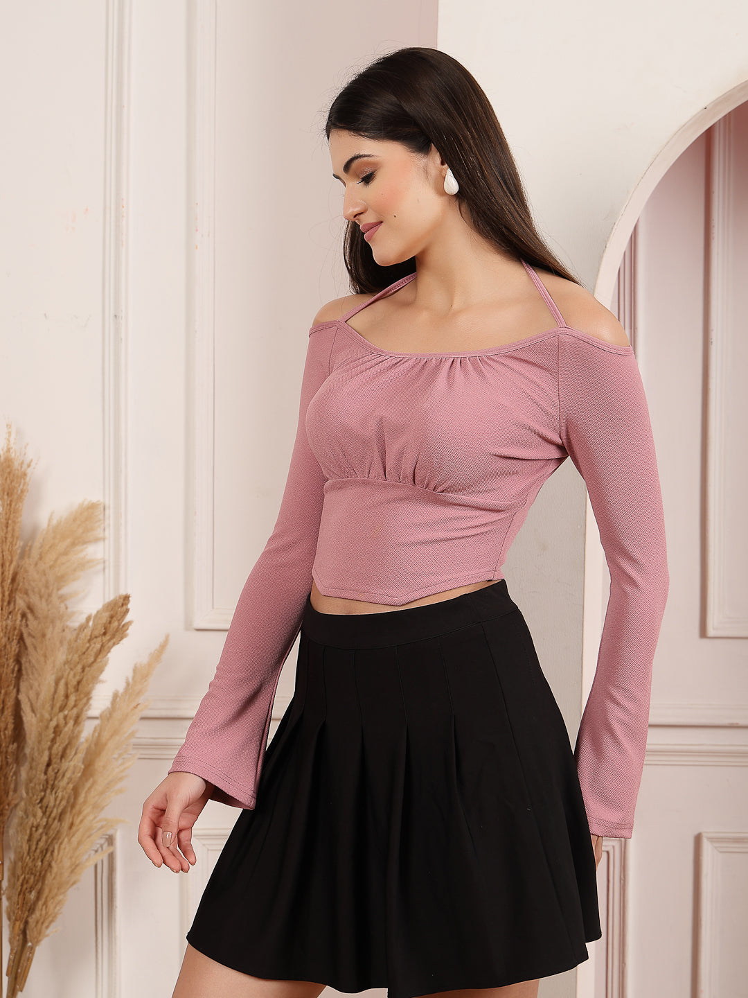Woman wearing a Mauve long-sleeve top and black skirt in a neutral setting