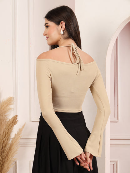 Woman wearing a beige off-shoulder top with long sleeves in a neutral setting