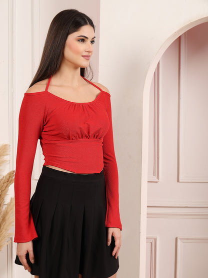 Woman wearing a red long-sleeve top and black skirt against a neutral background