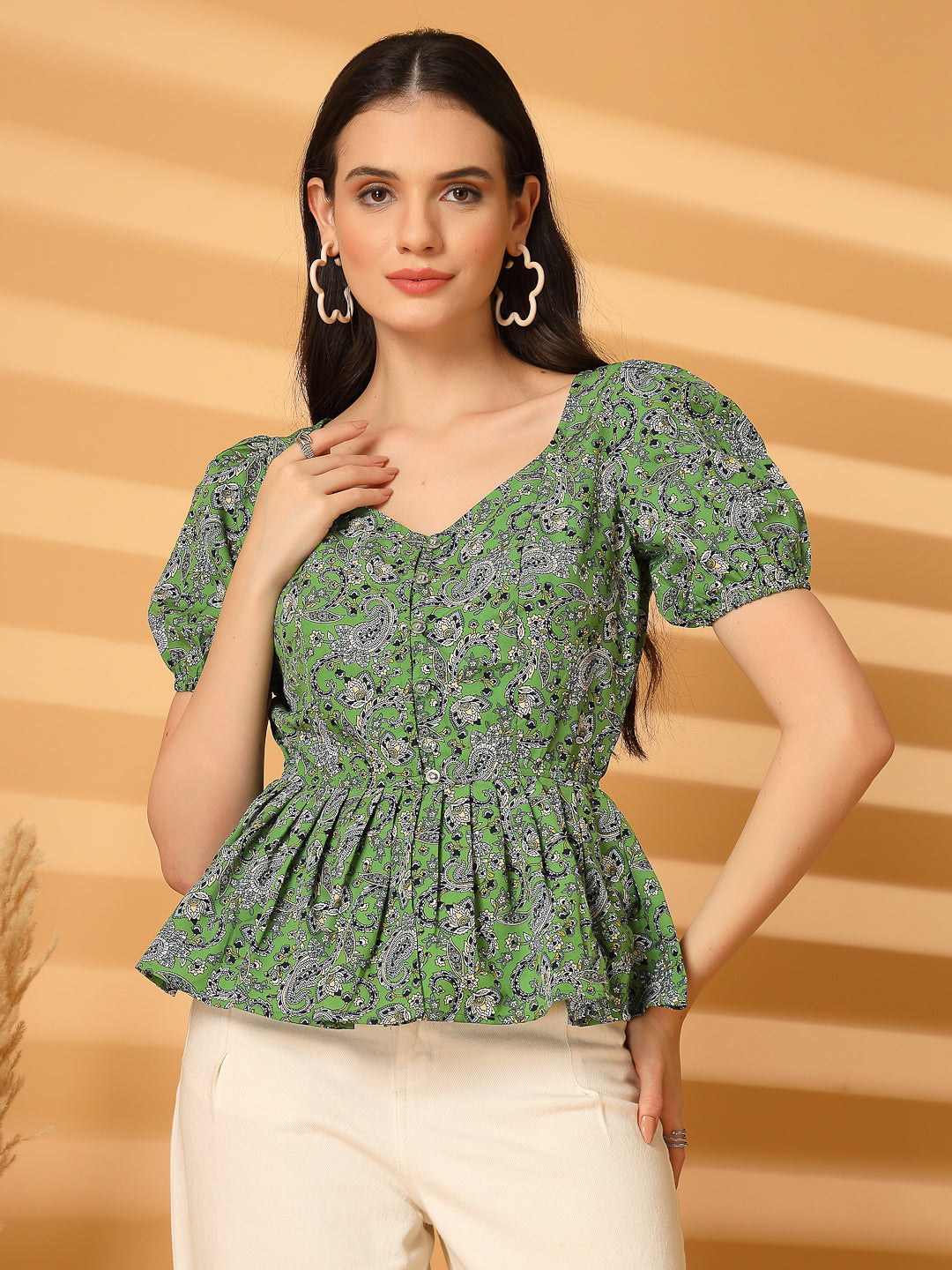 Woman wearing a green floral top against a beige background