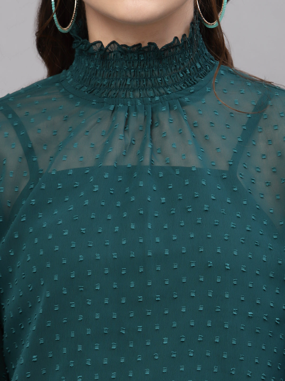 Green sheer top with textured pattern on a mannequin against a gray background