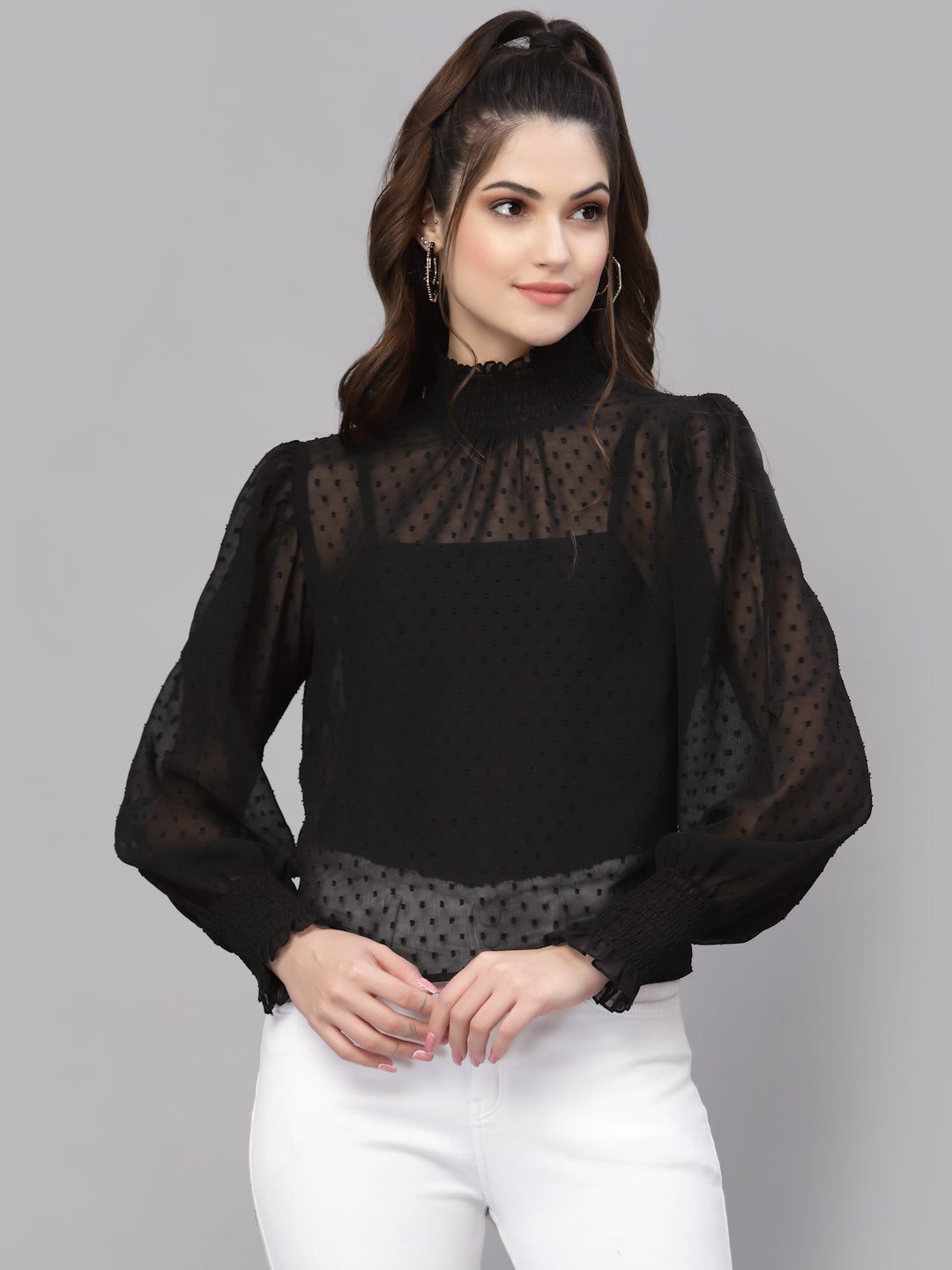 Woman wearing a black blouse with sheer sleeves on a gray background