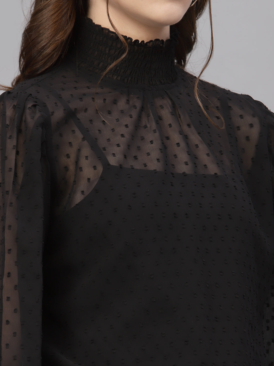 Black blouse with sheer polka dot overlay on a mannequin against a neutral background