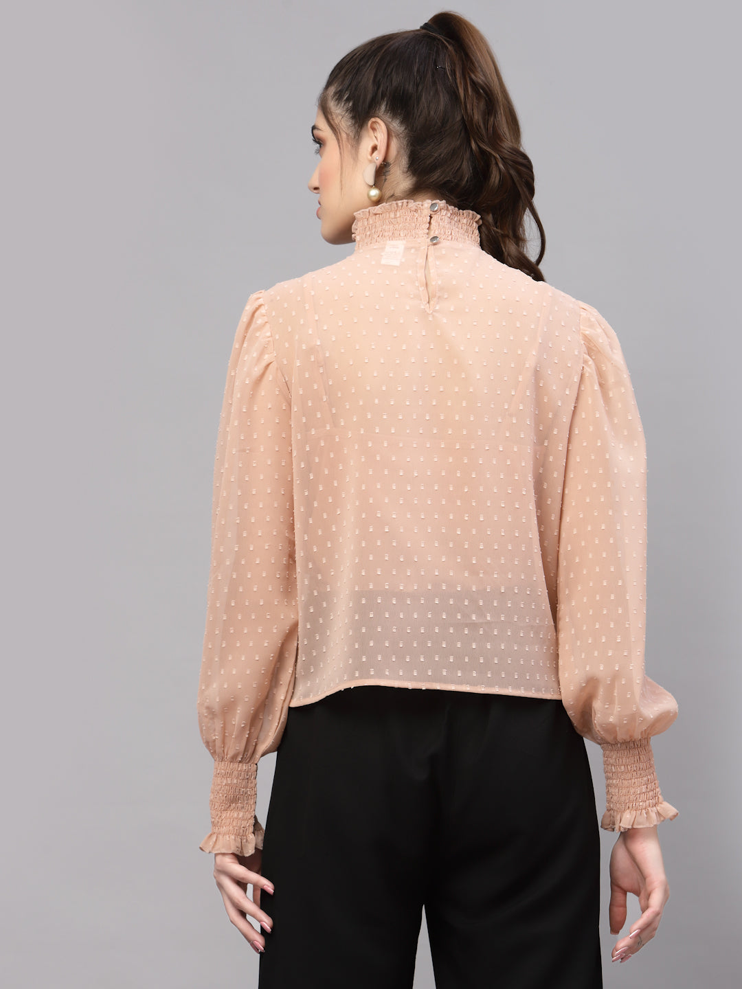 Woman wearing a beige blouse with a subtle pattern on a gray background