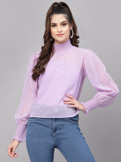 Woman wearing a purple top with long sleeves and blue jeans on a gray background