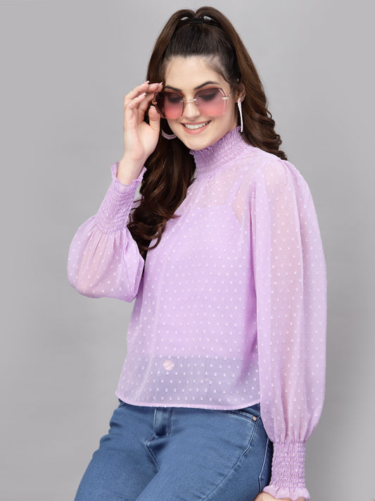 Woman wearing a light purple blouse with long sleeves and blue jeans on a gray background