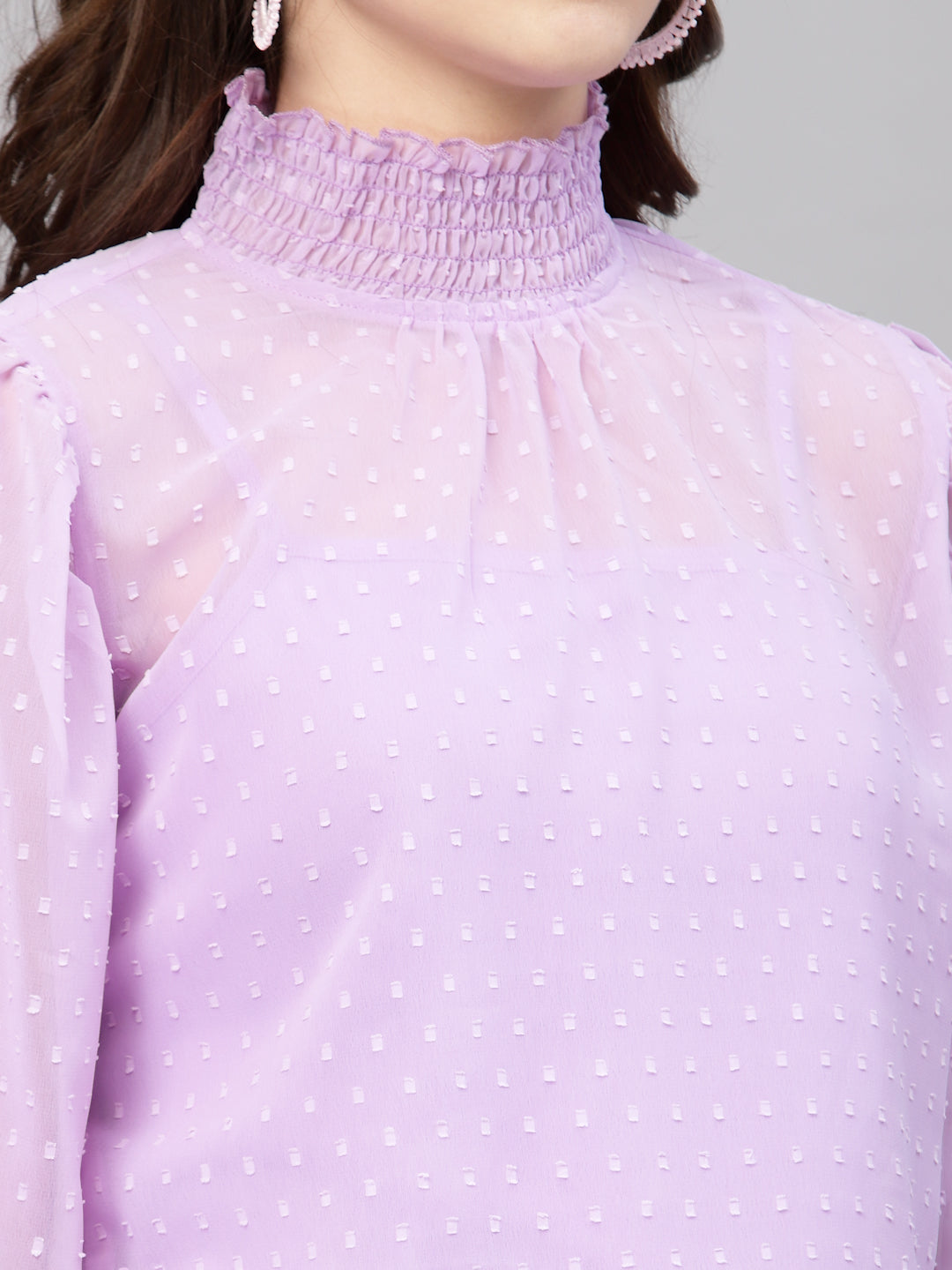 Close-up of a purple top with white polka dots on a mannequin.