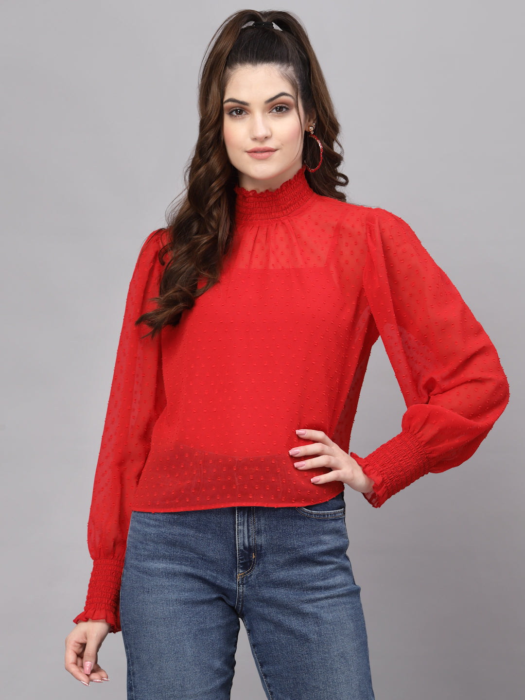 Woman wearing a red sweater and blue jeans on a gray background