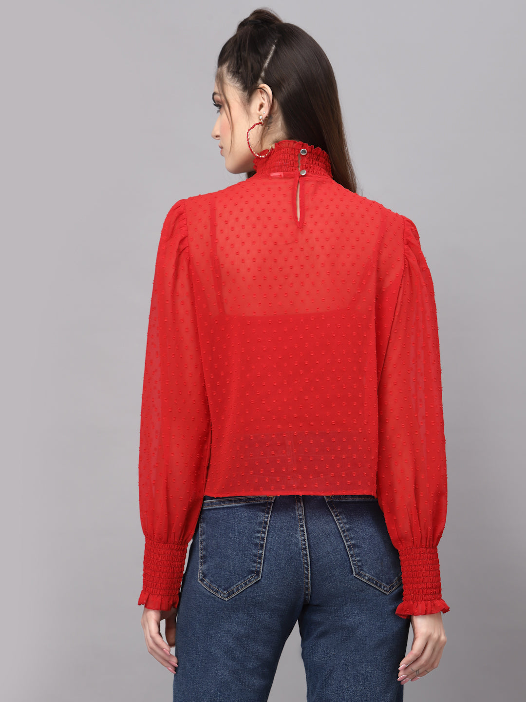 Red top with long sleeves and blue jeans on a gray background