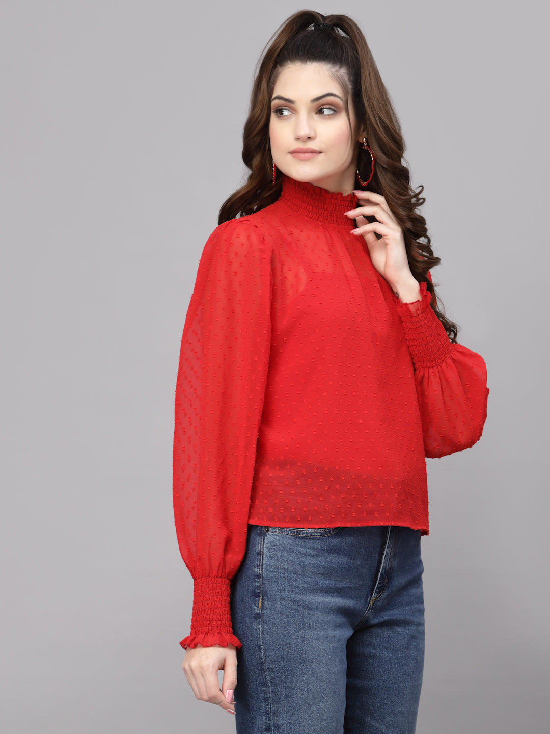 Woman wearing a red top and blue jeans on a gray background