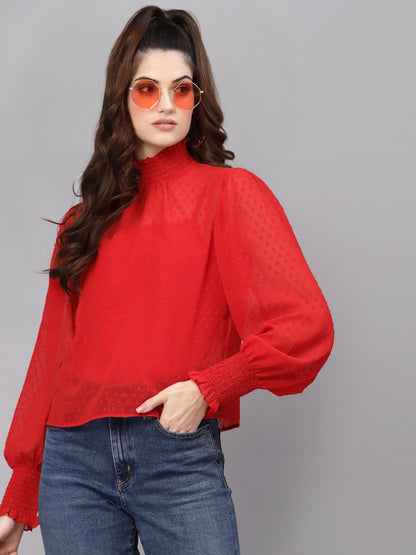 Woman wearing a red top and blue jeans against a gray background