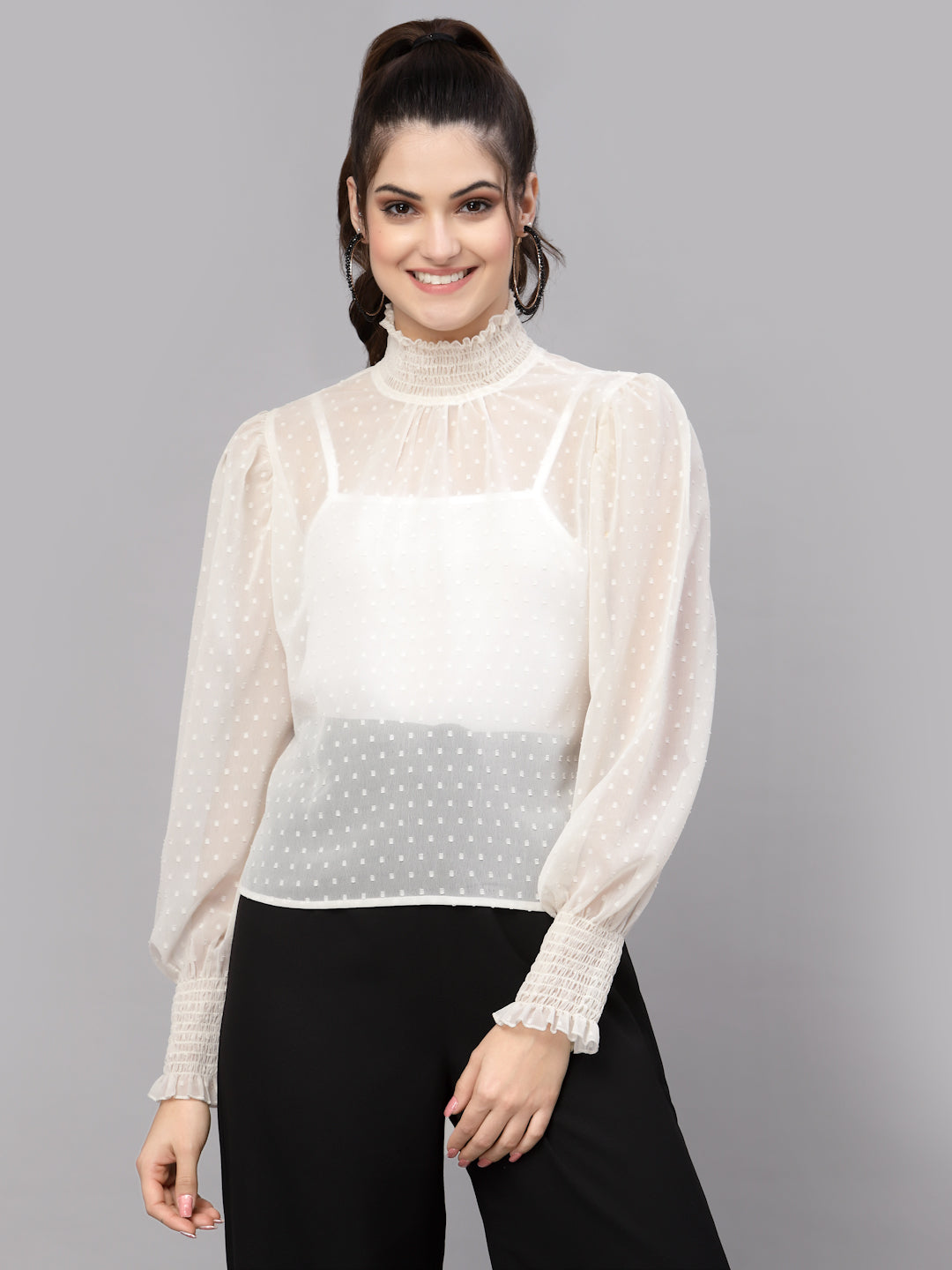 Woman wearing a white blouse with sheer sleeves on a gray background